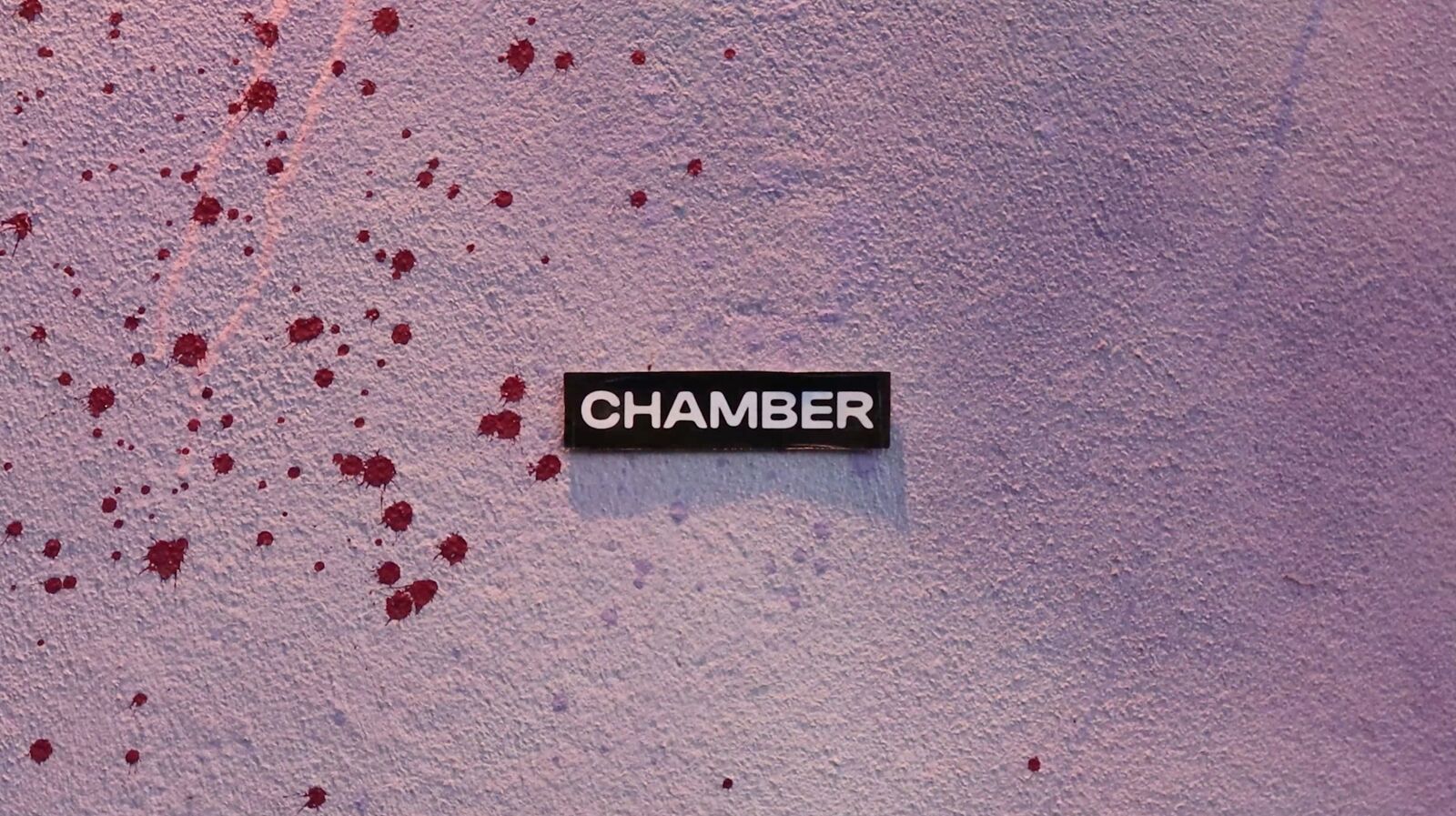 Chamber-klistremerke på lilla vegg med røde sprut