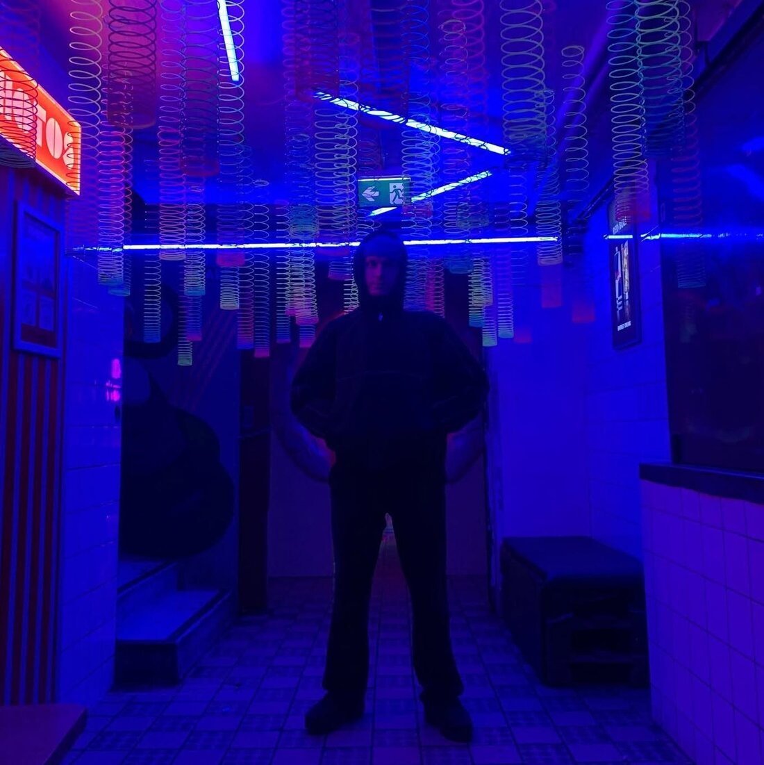 Fritz i hettegenser under blått neonlys og hengende slinkyer