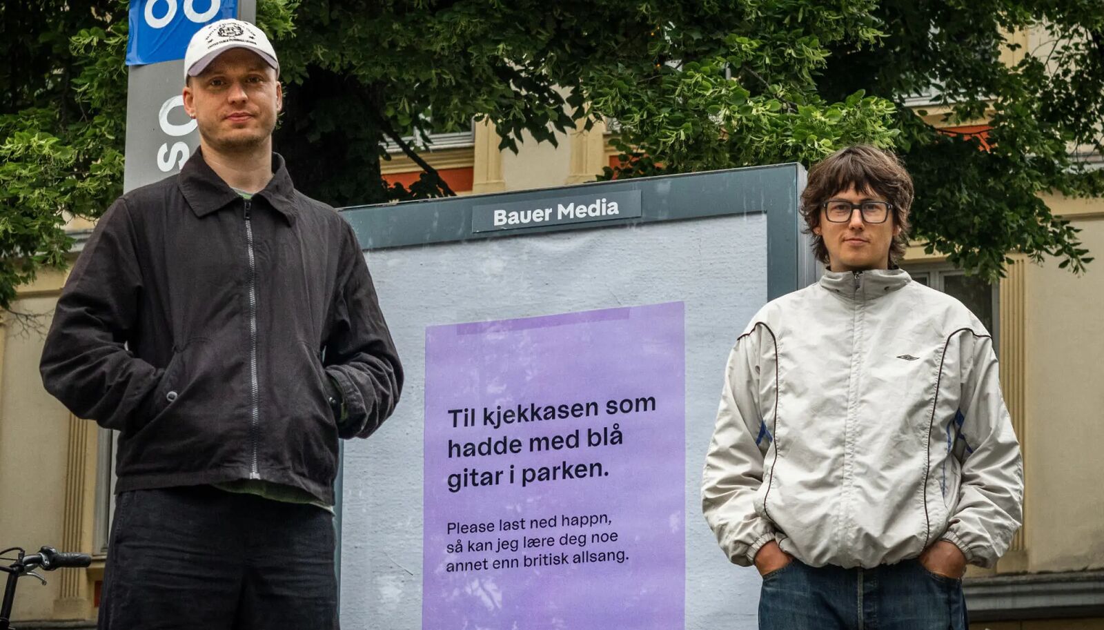 Fritz og Sigurd foran en lilla Happn-plakat på en Bauer Media-tavle i Oslo